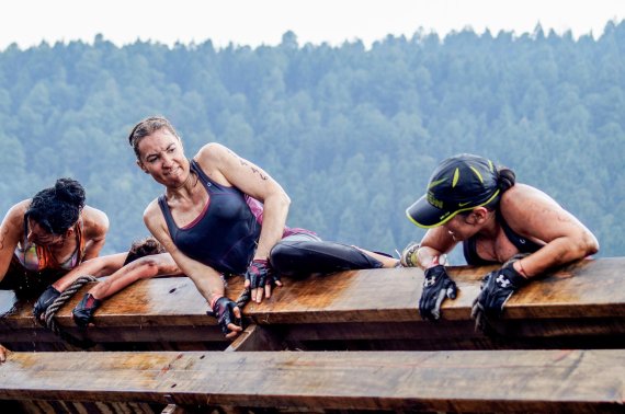 Three women climbing an obstacle