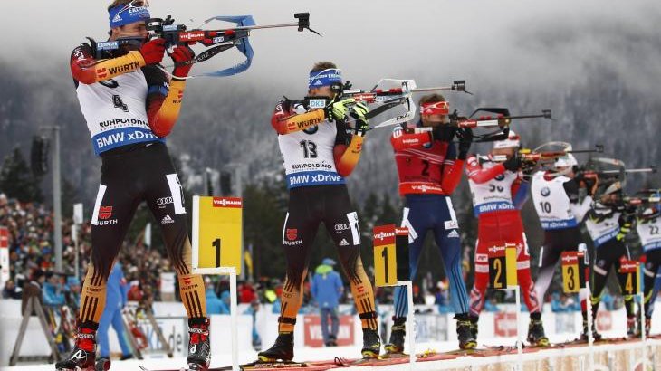 Biathletes stand in line and shoot.