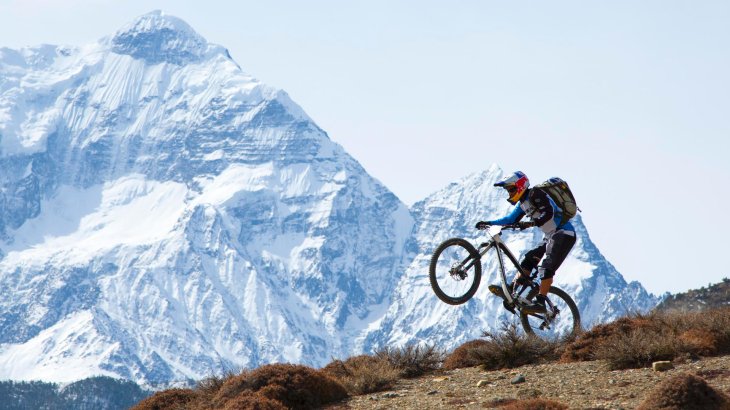 René Wildhaber macht einen Wheelie vor Bergpanorama.