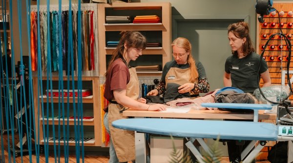 Drei Frauen stehen in einer Reparatur-Werkstatt von Globetrotter.